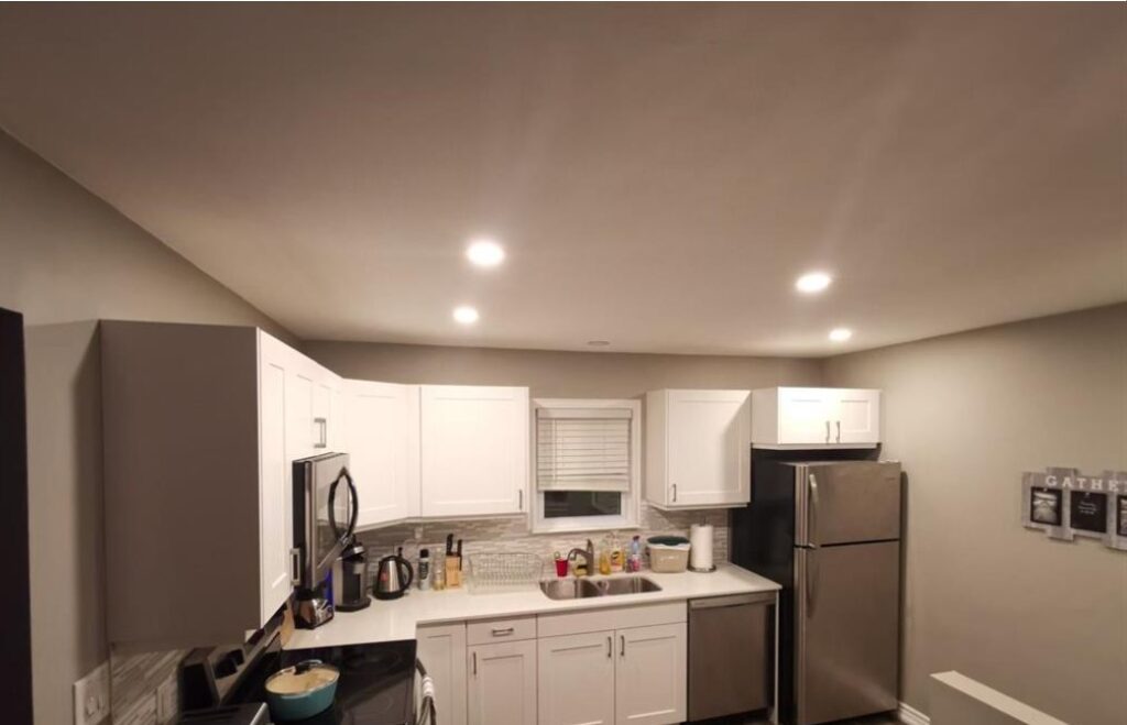 Poorly lit real estate listing photo of a kitchen with cluttered counters and harsh overhead lighting, showing how photos can misrepresent a home.