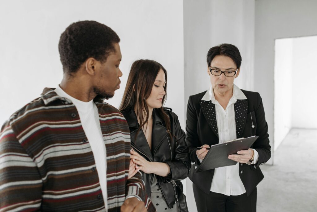 A real estate agent showing documents to a couple during a home tour, representing the value of local expertise in finding the right home.
