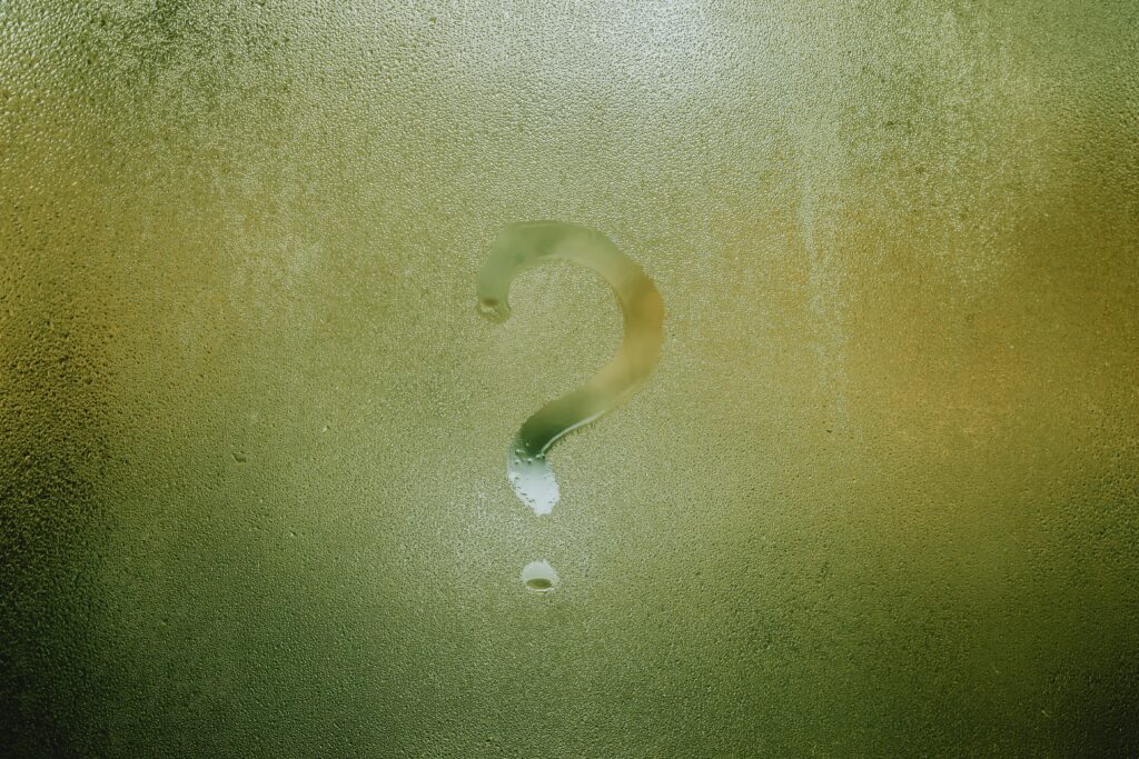 A question mark drawn on a foggy glass surface, symbolizing confusion or uncertainty.