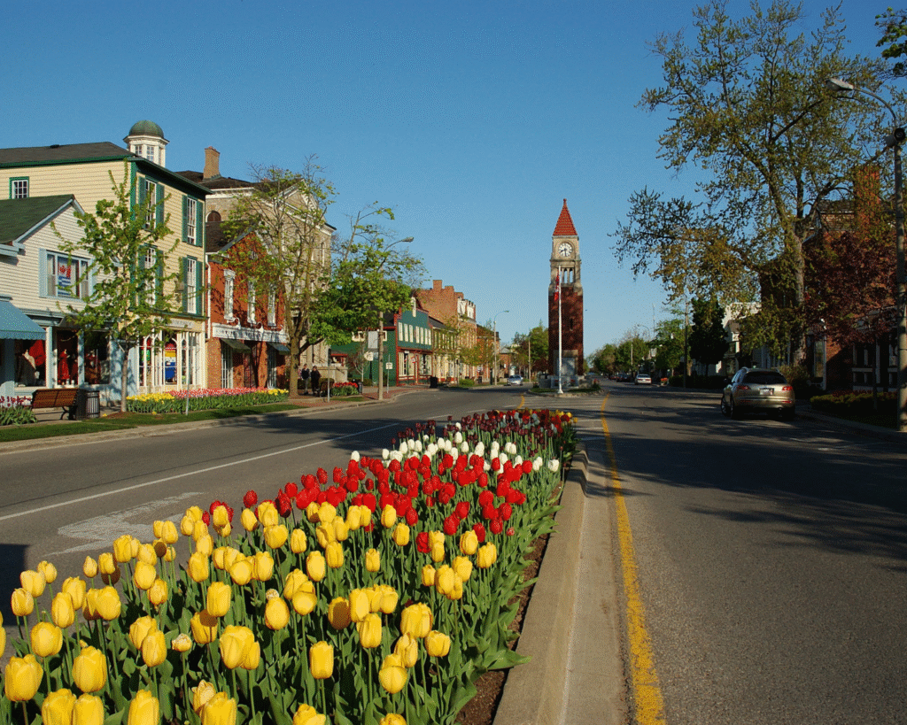 Niagara-on-the-Lake streetscape with tulips, heritage buildings, and the town clock tower.